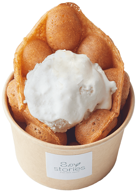 普通サイズのワッフルホイップ。きつね色に焼かれ、チョコソースと粉糖がまぶされたバブルワッフルが軽く丸められている。その間に白いホイップクリームがアイスクリームのように丸められてトッピングされている。